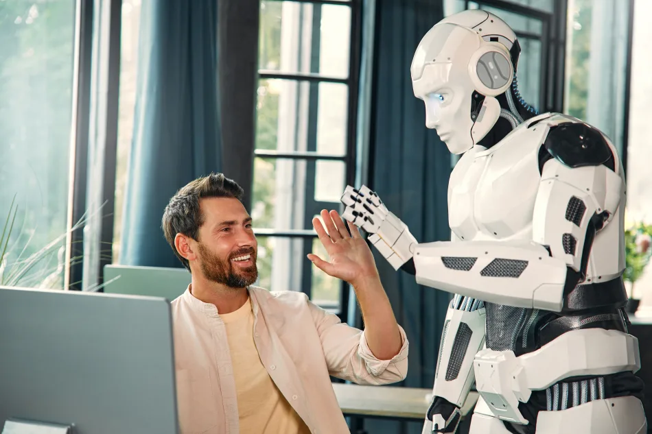 Uomo che dà il cinque a un robot umanoide in un ambiente di lavoro moderno.