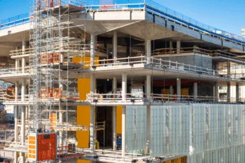 Costruzione di un edificio moderno con struttura in cemento armato, ponteggi e ascensore da cantiere.