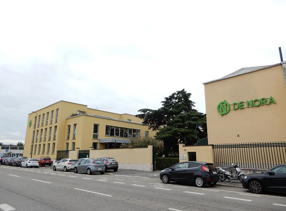 Edificio della sede di Industrie De Nora a Milano, vista esterna con parcheggio e logo aziendale visibile.