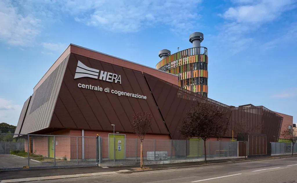 Centrale di cogenerazione HERA con struttura architettonica moderna e torre colorata sullo sfondo.
