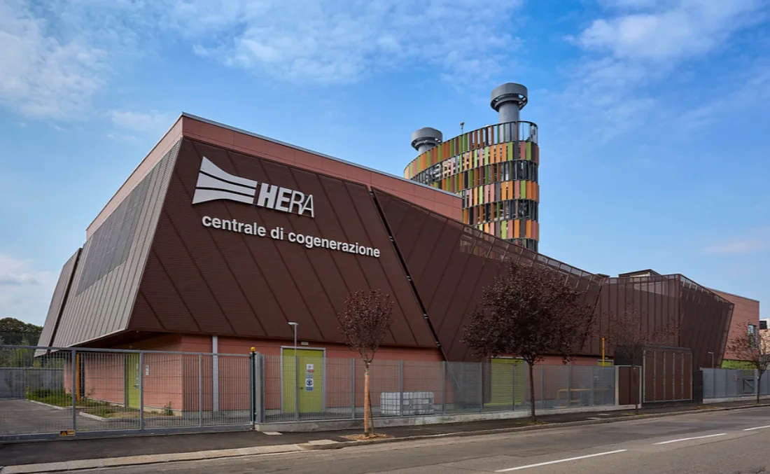 Centrale di cogenerazione HERA con struttura architettonica moderna e torre colorata sullo sfondo.