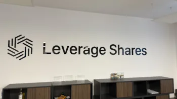 Logo e insegna Leverage Shares su parete bianca all’interno dell’ufficio, con arredi moderni e premi aziendali esposti.