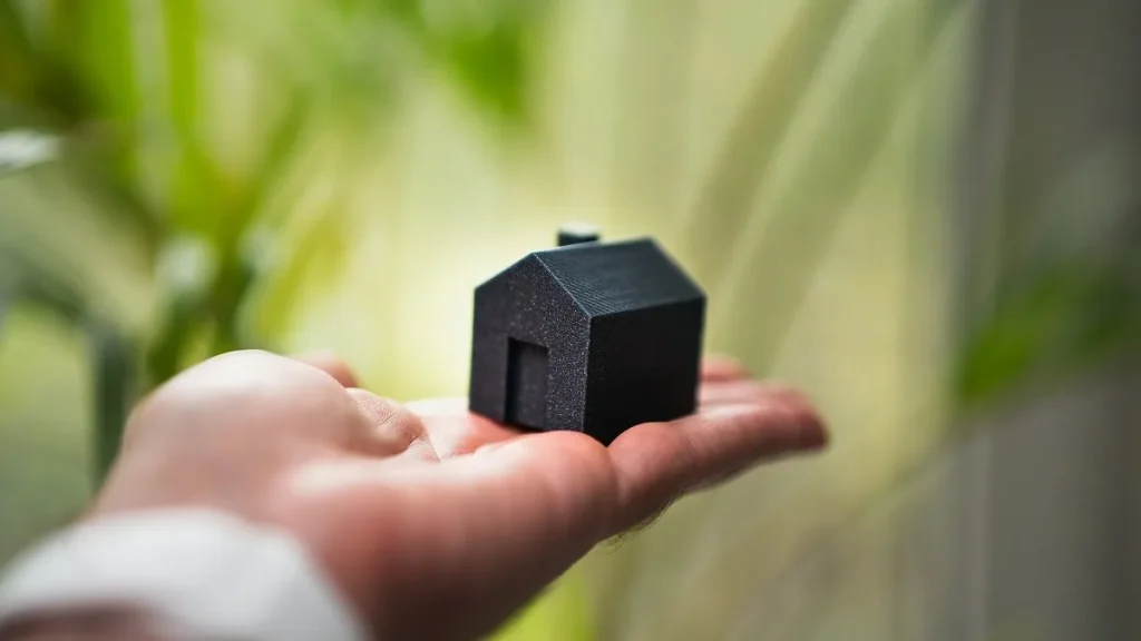 Una persona tiene in mano una piccola casa, simbolo del mercato immobiliare