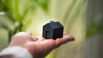 Una persona tiene in mano una piccola casa, simbolo del mercato immobiliare