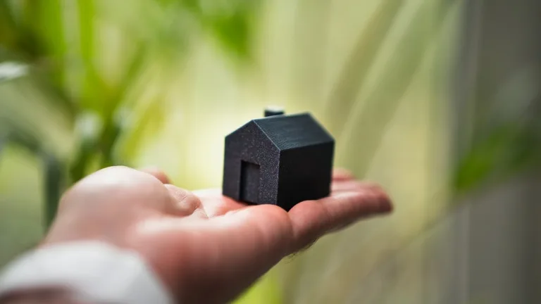 Una persona tiene in mano una piccola casa, simbolo del mercato immobiliare