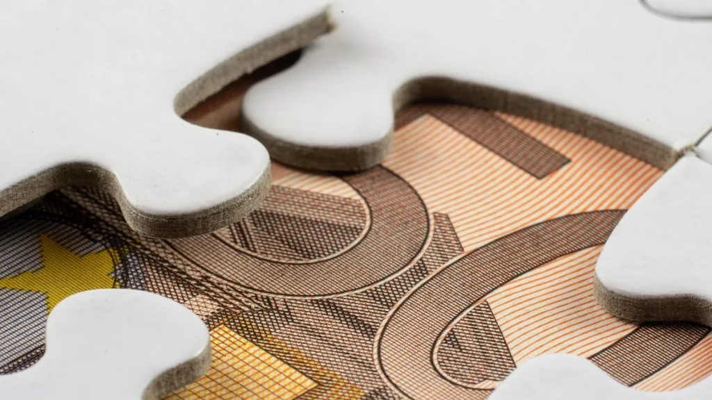 Una banconota da 50 euro sotto i tasselli di un puzzle