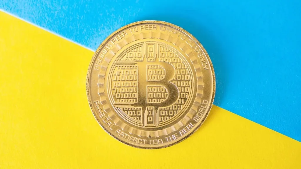 Un token Bitcoin con i colori della bandiera dell'Ucraina sullo sfondo