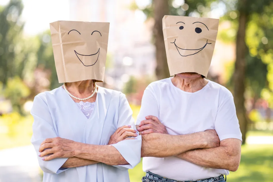 Due persone anziane si sono messe in testa una busta di carta del pane con disegnate sopra due facce sorridenti