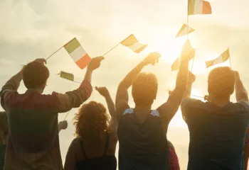 Persone che sventolano bandierine italiane al tramonto durante un evento patriottico