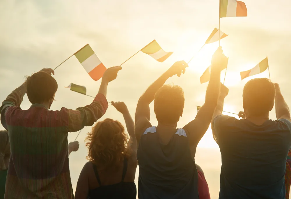 Persone che sventolano bandierine italiane al tramonto durante un evento patriottico