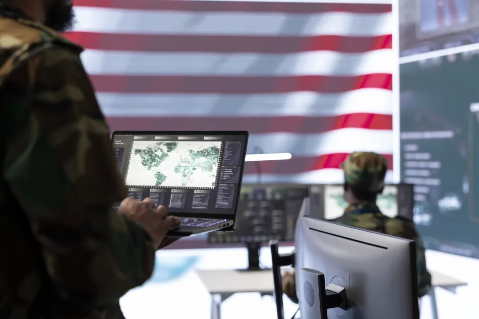 Ufficiali dell’esercito USA al lavoro in un centro di comando cibernetico con mappa strategica globale su laptop