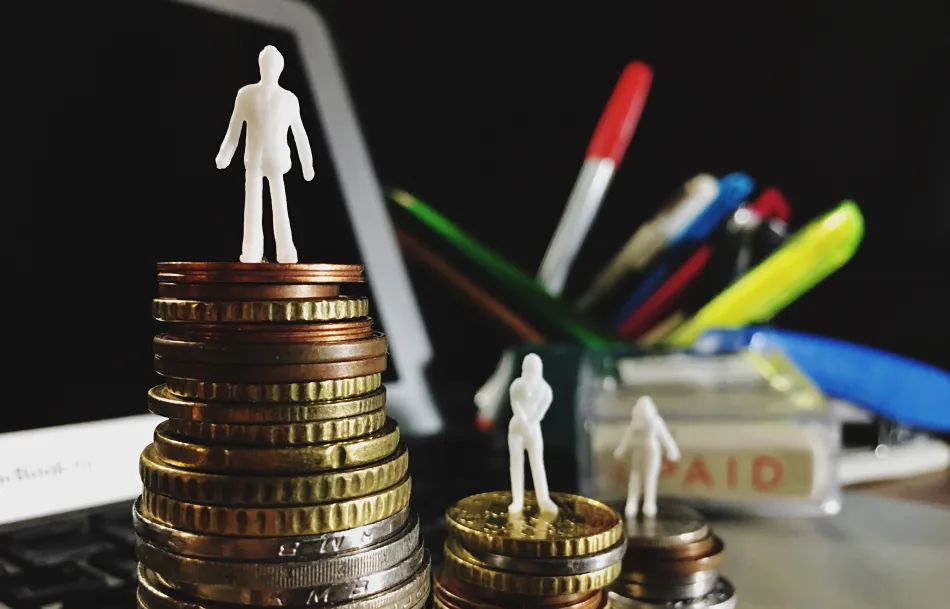 Miniature di persone in piedi su pile di monete di diverse altezze