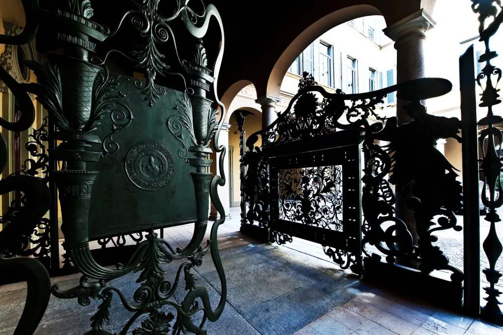 Cancello in ferro battuto decorato con stemma e motivi ornamentali all’ingresso di un palazzo storico italiano ì, sede di Mediobanca