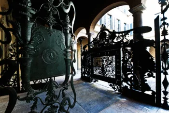 Cancello in ferro battuto decorato con stemma e motivi ornamentali all’ingresso di un palazzo storico italiano ì, sede di Mediobanca