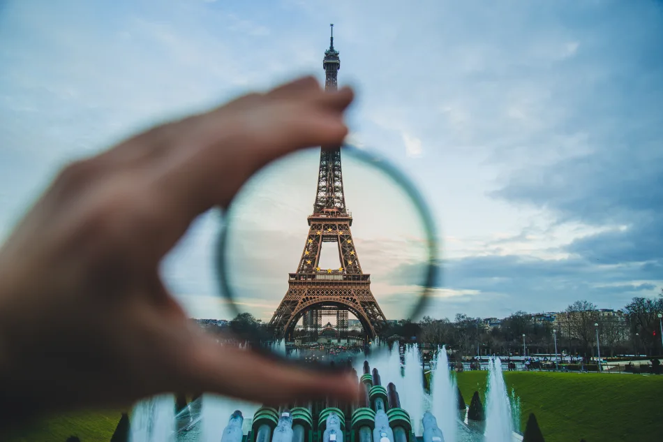 La Torre Eiffel a Parigi, inquadrata in un filtro fotografico tenuto tra le dita di una mano