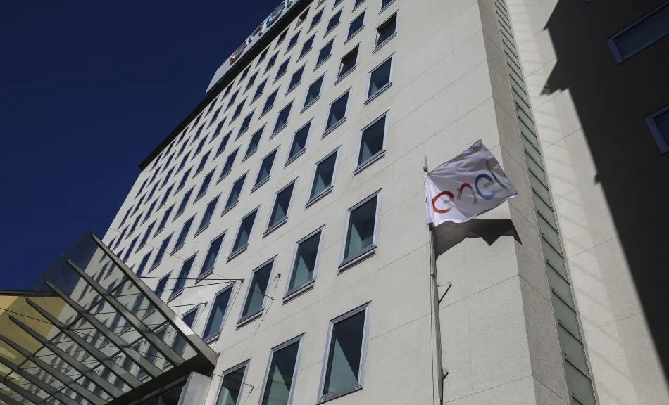 Esterno della sede Enel a Milano, con il logo dell'azienda visibile sulla facciata e la bandiera che sventola.