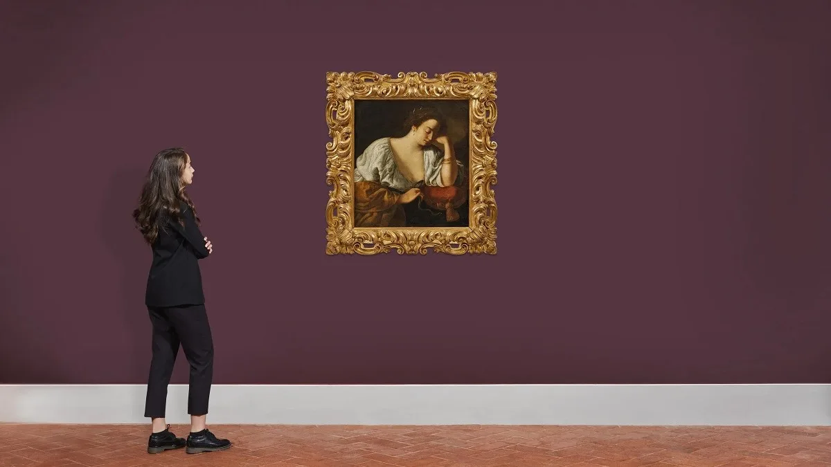 Una donna ammira il dipinto Cleopatra di Artemisia Gentileschi