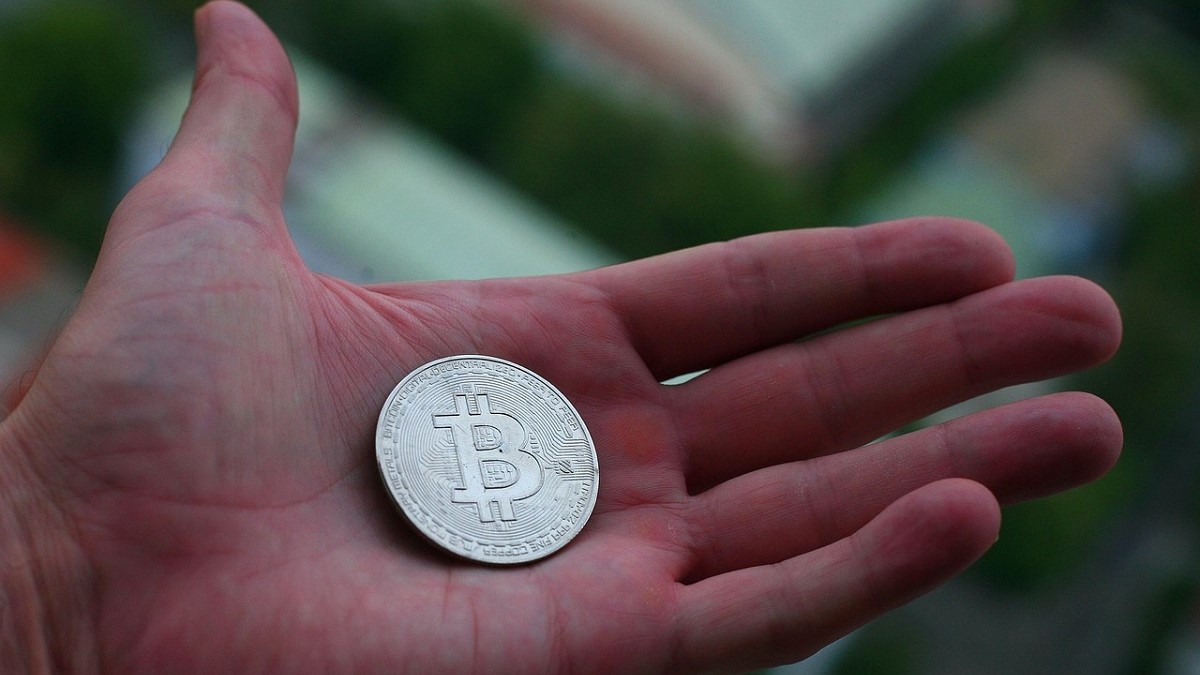 Una persona tiene in mano un token di Bitcoin