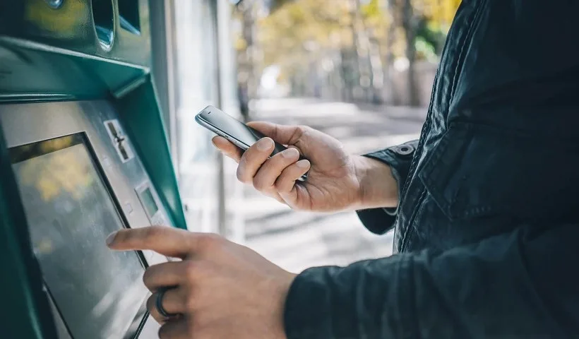 Una persona preleva al Bancomat con il suo smarphone