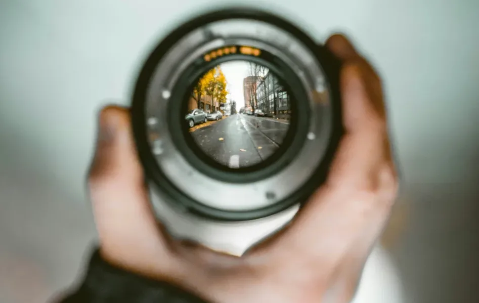 Obiettivo fotografico, al cui interno si vede una strada mentre tutt'intorno all'obiettivo il panorama è sfocato