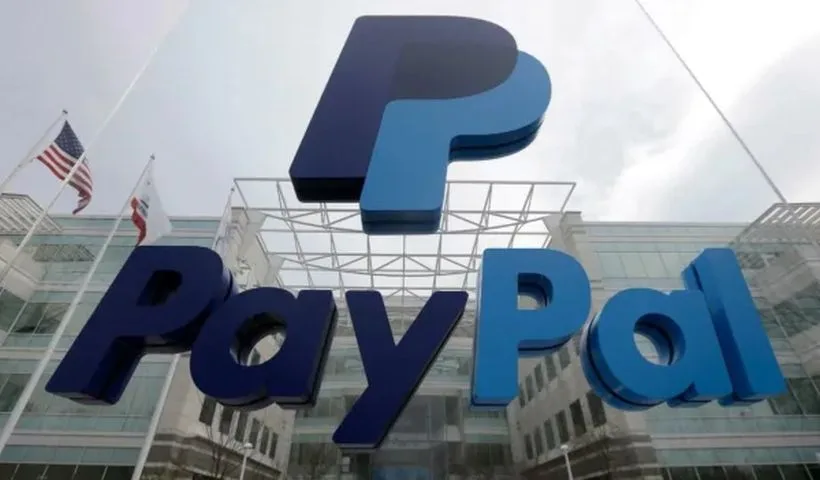 In primo piano il logo di PayPal, gigante, sospeso davanti alla sede della società