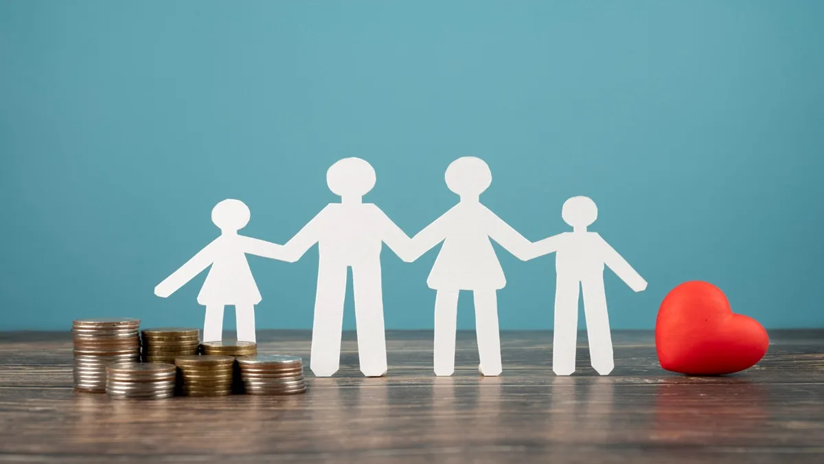 Sagome di una famiglia con due bambini, monete impilate e un cuore rosso su sfondo azzurro, concetto di sostegno economico e assegno unico 2026 per le famiglie