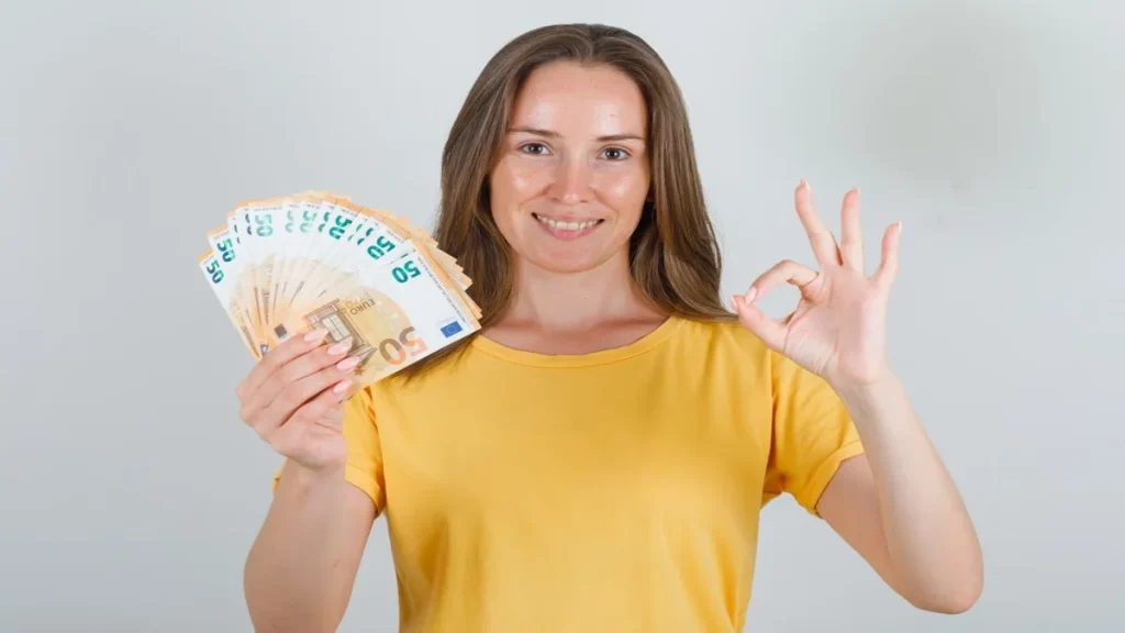 Donna sorridente mostra banconote; simbolo del pagamento del Bonus Mamme 2025 erogato dall’INPS