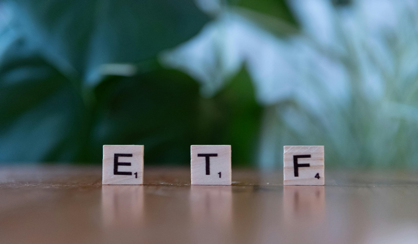 Tre tessere del gioco dello Scarabeo in piedi, compongono la parola ETF