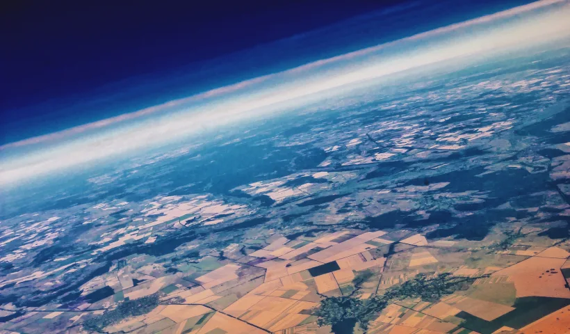 Un'immagine della terra scattata da un satellite in orbita. Visibile l'atmosfera e il suolo, con campi coltivati