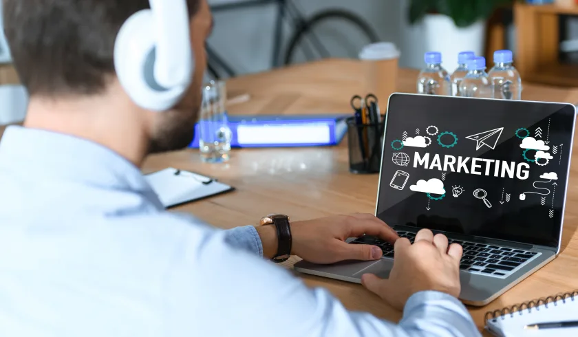 Un manager seduto alla scrivania. Davanti a lui un laptop aperto con la scritta marketing
