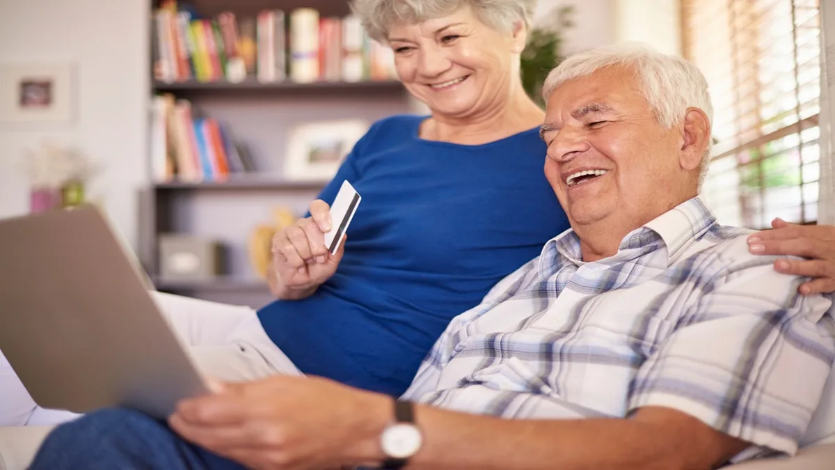 Coppia di anziani felice mentre usa un laptop per informazioni sulle pensioni