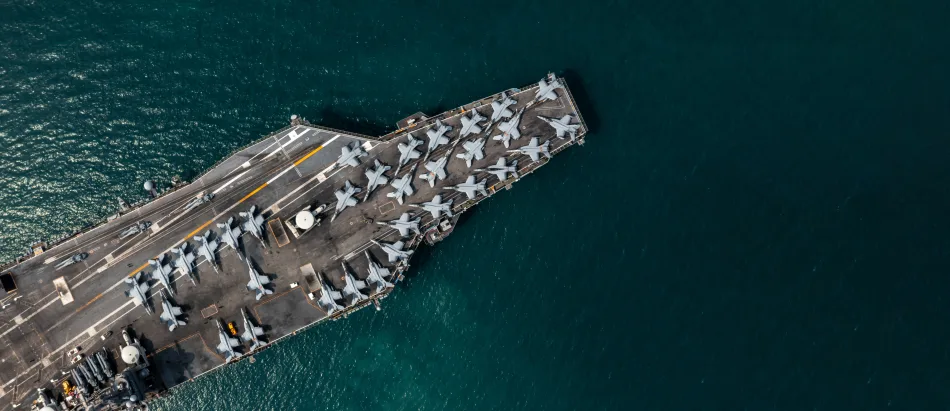 Vista aerea di una portaerei in navigazione. Sul ponte, file di jet pronti al decollo
