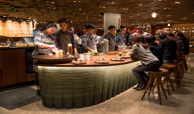 La Starbucks Roastery di Shanghai in Cina. Diversi avventori siedono intorno a un tavolo ovale, effettuando una degustazione