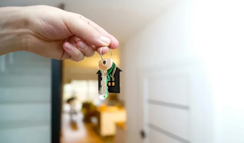 Mano che consegna le chiavi di una nuova abitazione con portachiavi a forma di casa, simbolo di acquisto immobiliare e bonus casa