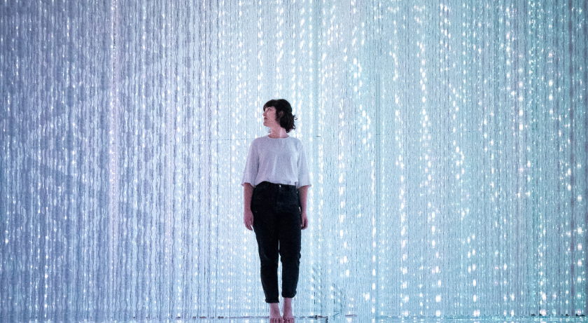 Una donna in piuedi al centro di una cascata di byte digitali