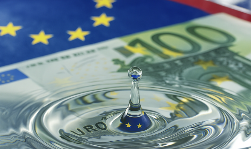 Una goccia cade su una banconota in euro, generando delle onde simili a quelle che si generano sull'acqua. Nella parte superiore della foto, la bandiera dell'Unione europea