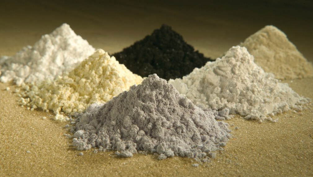 Mucchietti di ossidi di terre rare di colori diversi su una superficie neutra