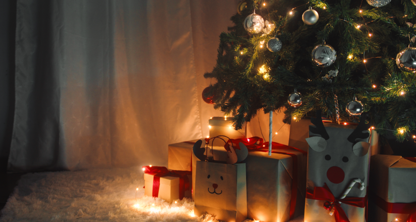 Sotto un albero di Natale illuminato dalle luminarie sono posizionati vari regali