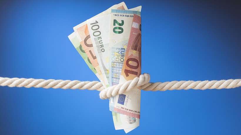 Banconote legate con una corda a rappresentare il taglio dell’importo dell’Assegno di Inclusione 2026 previsto al rinnovo del beneficio.