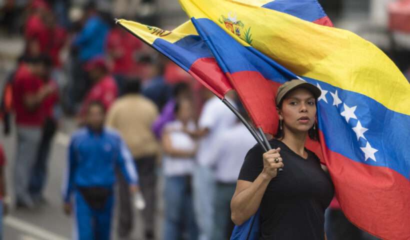 Immagine di una donna con la bandiera venezuelana durante una manifestazione