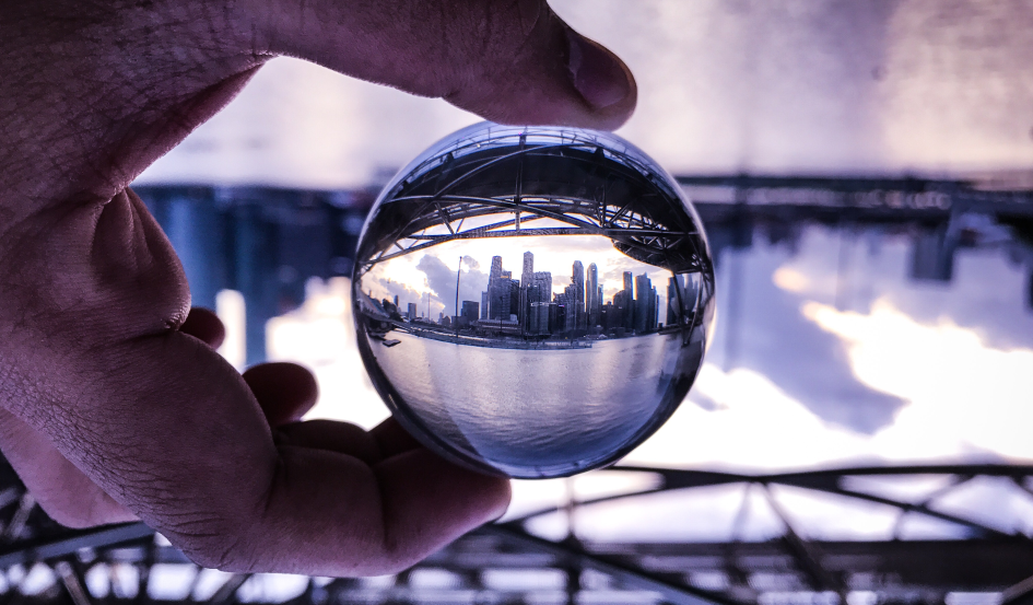 Una sfera di vetro tenuta tra le dita di una mano mostra i grattacieli della city, in lontananza. Attorno a lei il panorama è sfuocato