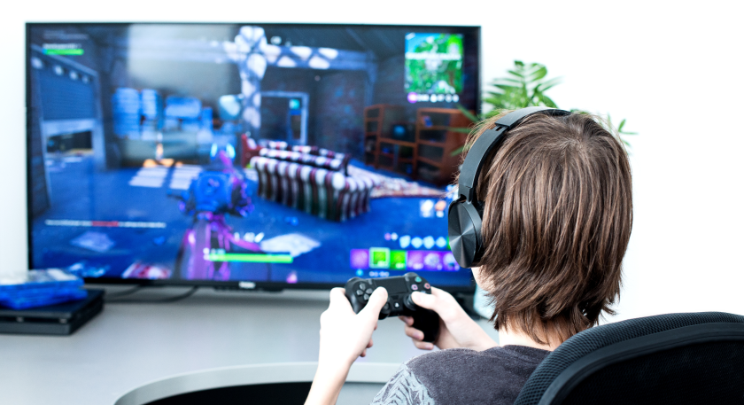 Un ragazzo, di spalle, seduto a una scrivania, sta giocando a un videogioco