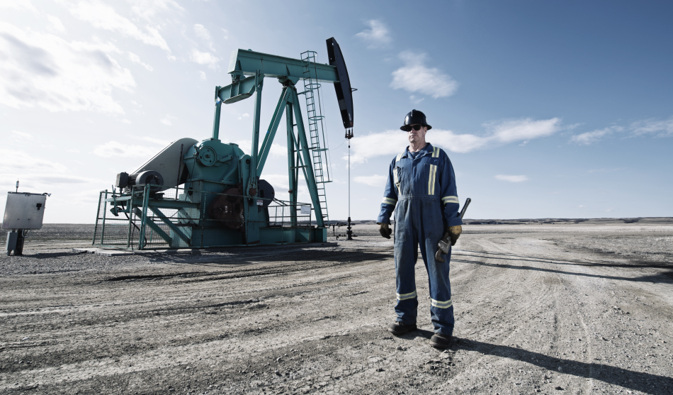 Un pozzo petrolifero e un operaio che cammina in sua direzione