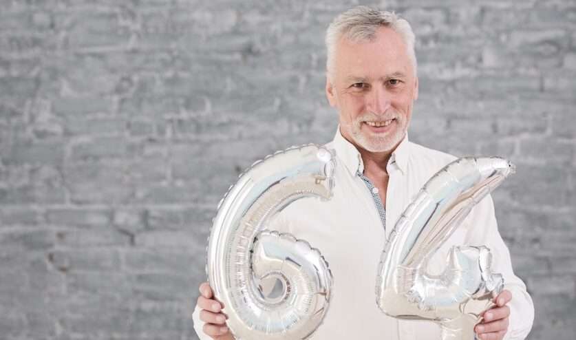 Uomo di 64 anni con palloncini numerici, simbolo della pensione anticipata a 64 anni nel 2026