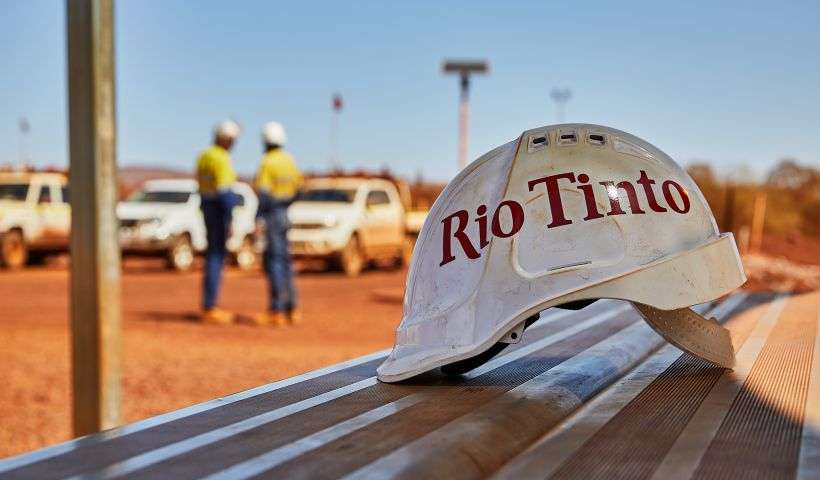 una foto di un casco targato Rio Tinto con dietro due operatori della società