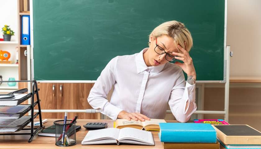 Docente che consulta documenti alla scrivania per capire le novità della carta docenti
