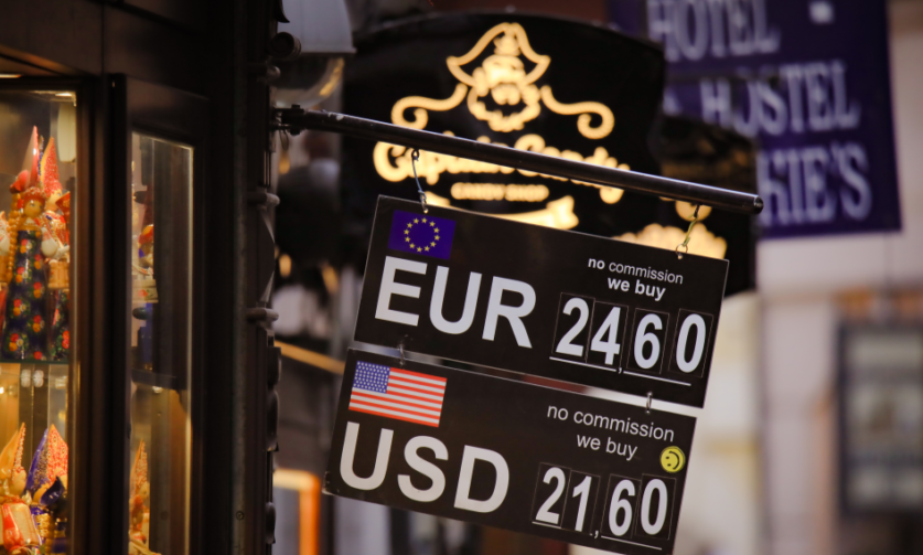 Un cartello appeso all'esterno di un negozio mostra il tassi di acquisto e vendita di euro e dollari.