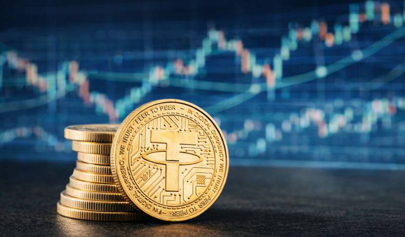 Primo piano fotografico di una moneta Tether (USDT) appoggiata su un desk di trading, con sullo sfondo sfocato grafici di mercato e candele finanziarie