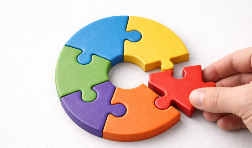 Puzzle circolare a cinque pezzi colorati, con una mano che inserisce l’ultimo tassello rosso: concetto di portafoglio diversificato e strategie d’investimento integrate.