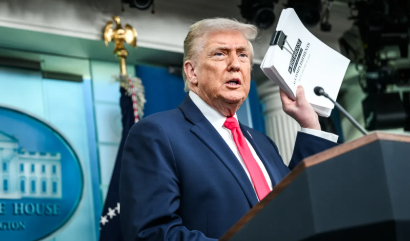 Il presidente Usa, Donald Trump, in un discorso alla Casa Bianca, alza con la mano sinistra un pacchetto di fogli contenenti un provvedimento legislativo